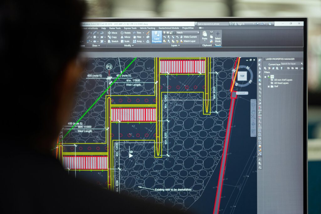 pexels-photo-3862379-3862379 A civil engineer working on a weir design using CAD software on a computer screen in an office setting.